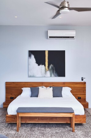 Ein Schlafzimmer mit einem hölzernen Bett, einem Deckenventilator, einer Klimaanlage und einem Wandbild.