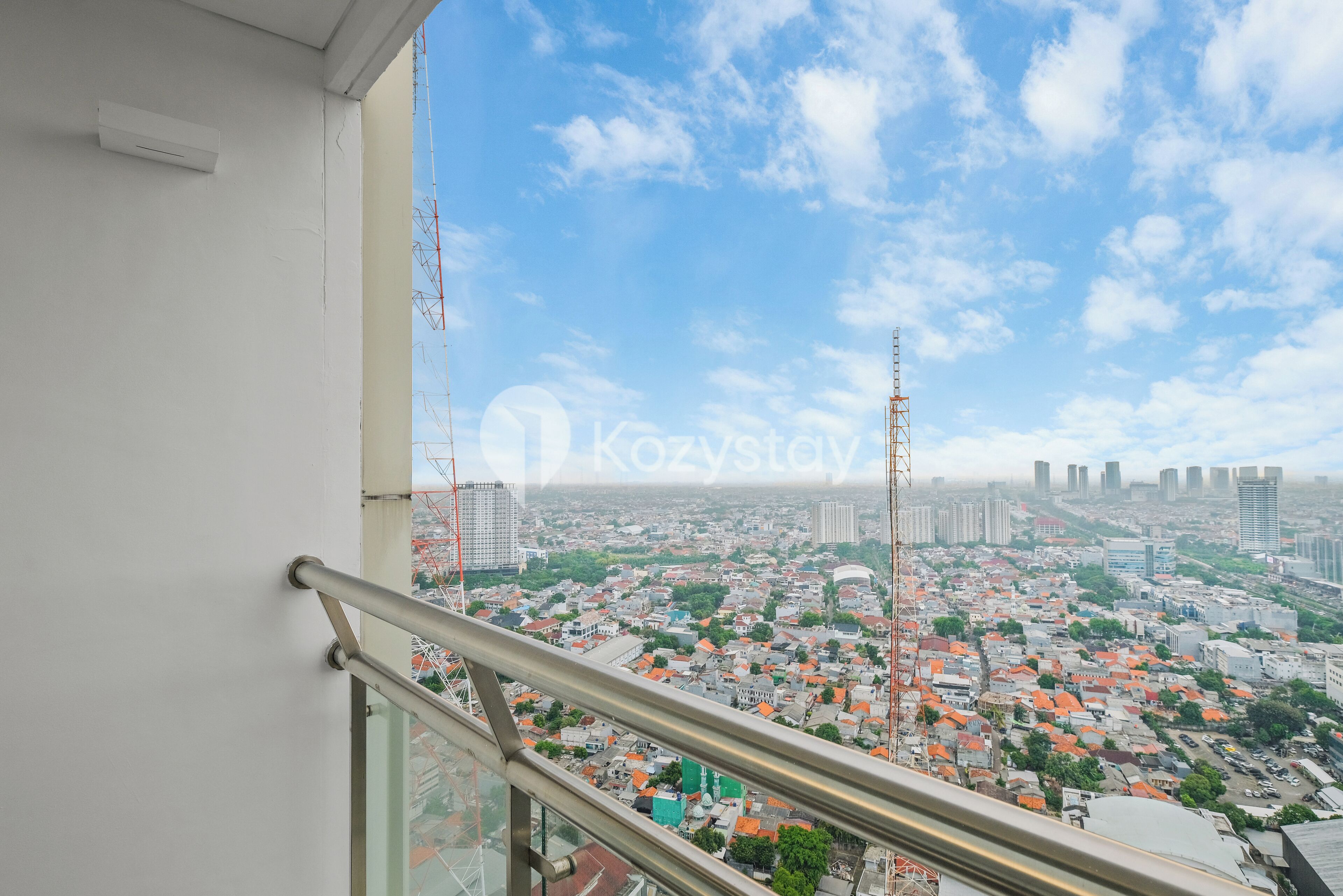 A cityscape view from a high-rise building with a metal railing in the foreground.