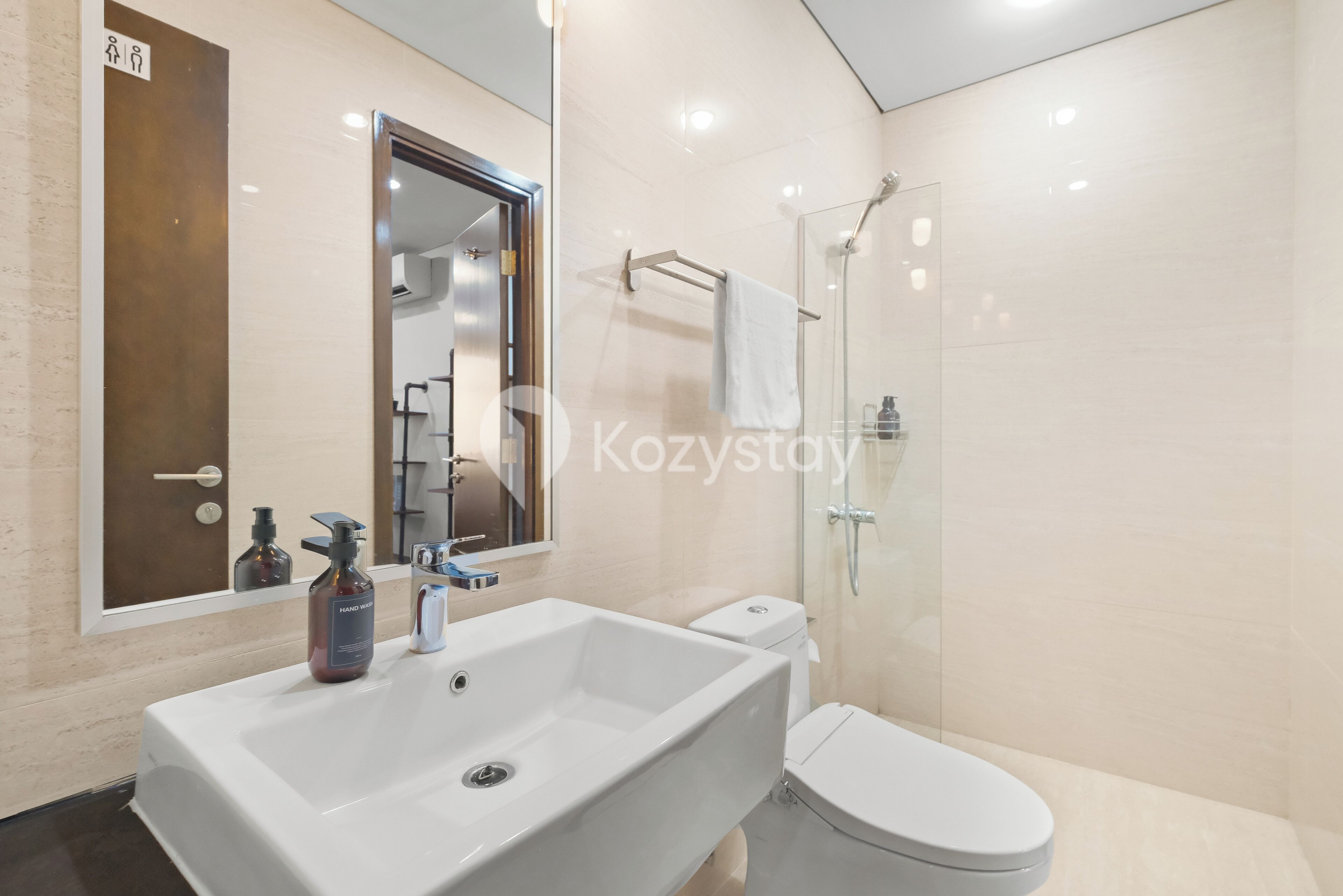 Un baño moderno con un lavabo blanco grande, un inodoro y una ducha con mampara de vidrio.