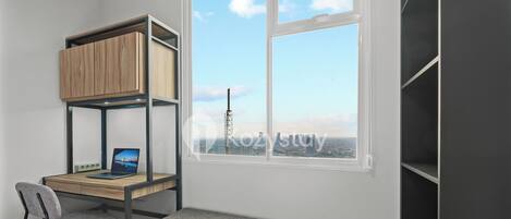 A bedroom with a bunk bed, a desk with a laptop, a chair, and a window with a city view.