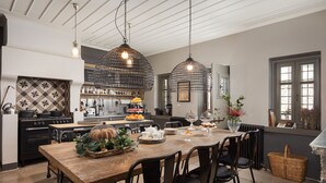 Een moderne keuken met een houten eettafel, hangende pendantlampen en uitzicht naar buiten.