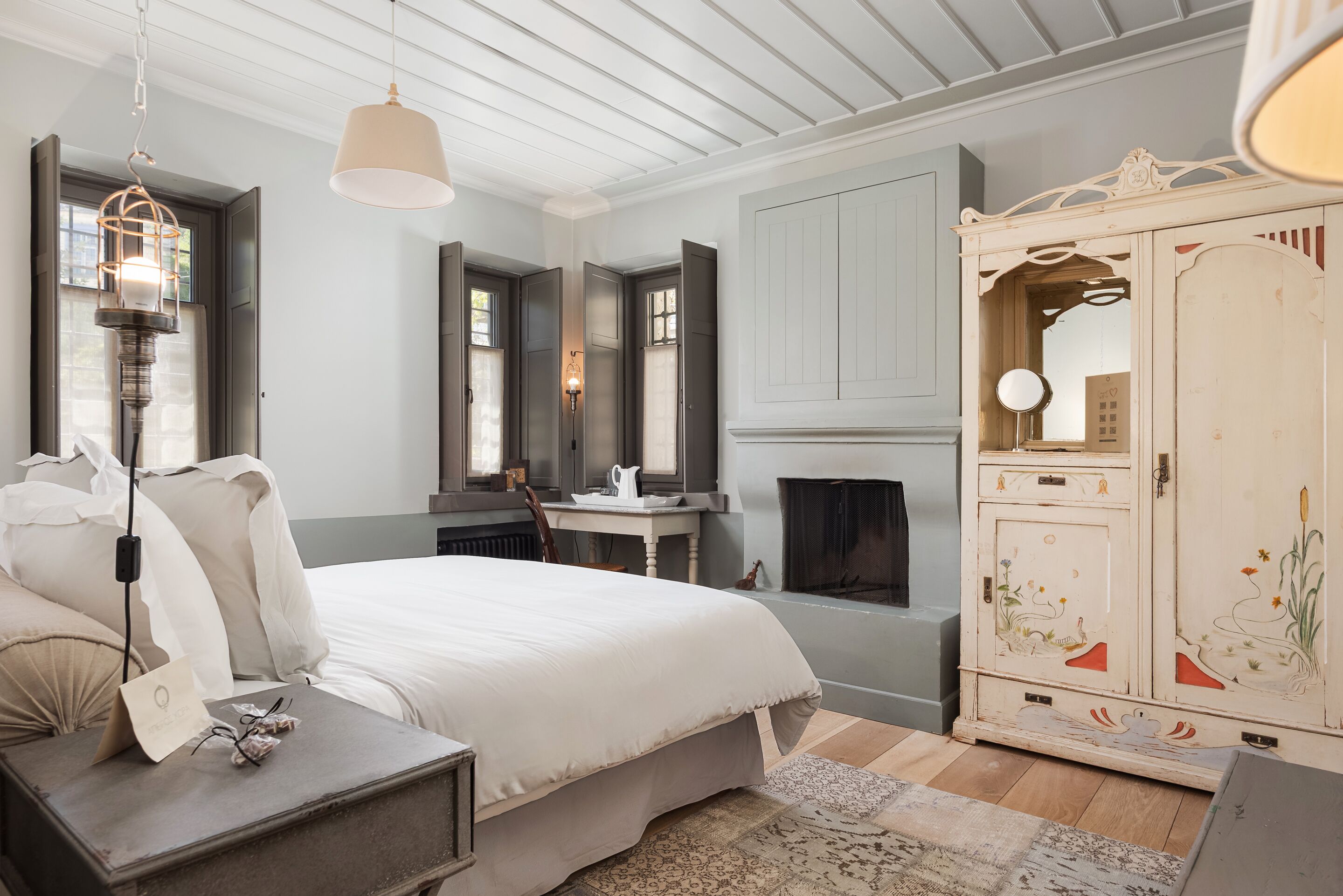 A bedroom with a bed, bedside table, lamp, wardrobe, and fireplace.