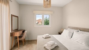 Un dormitorio con cama, escritorio, silla, ventana y lámpara colgante.