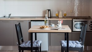 A modern kitchen with wooden cabinets, a stainless steel sink, and a dining table with two chairs.