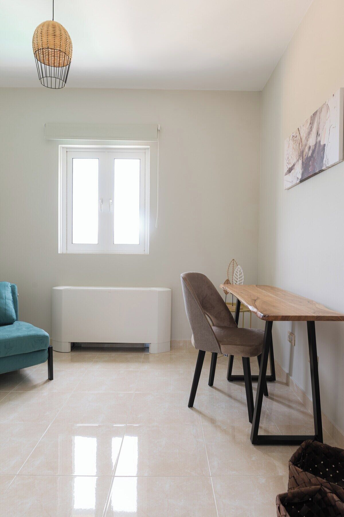A spacious room with a large window, a dining table, a sofa, and a radiator.
