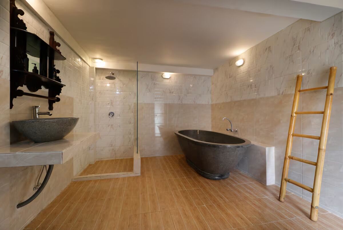 A modern bathroom with a freestanding bathtub, a glass-enclosed shower, and a wooden ladder.