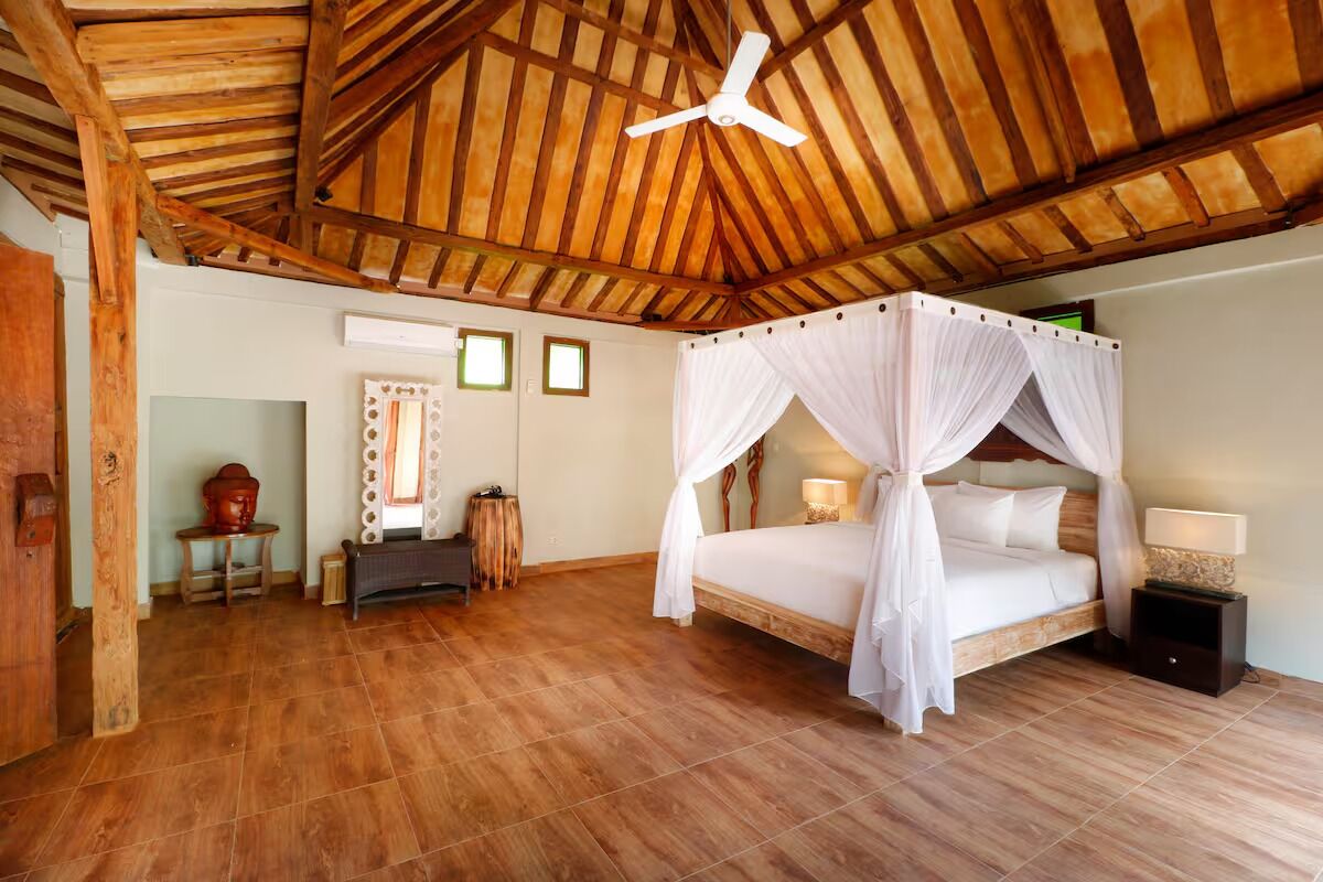 Une chambre spacieuse avec un plafond en bois, un lit à baldaquin et un ventilateur de plafond.