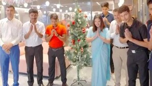 A group of people standing in a modern indoor space with a Christmas tree. - Hotel Bael Tree By Carlton Suites (Hyderabad)