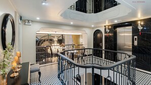 A modern hotel lobby with a central staircase, a chandelier, and a reception area. - Ella Riverside Lao Cai Hotel (Lao Cai)