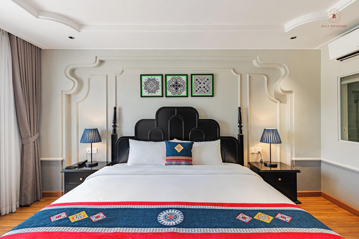 Habitación de hotel con una cama grande, dos mesitas de noche, un cabecero y tres obras de arte colgadas en la pared.