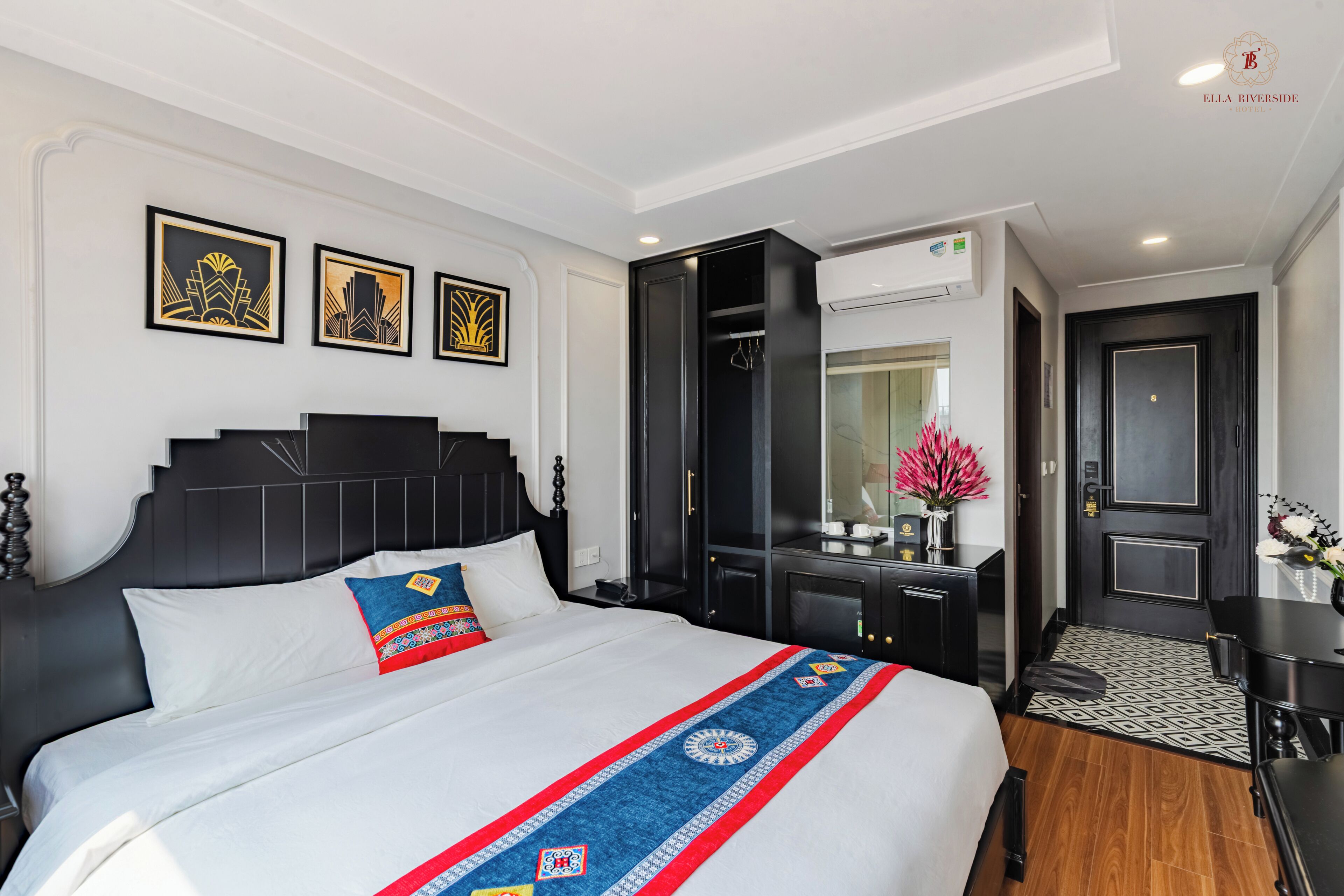 A modern hotel room with a large bed, a desk, and a wardrobe.