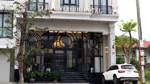 A multi-story hotel with a classic architectural design, featuring balconies and large windows. - Ella Riverside Lao Cai Hotel (Lao Cai)