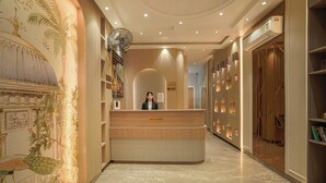 A reception area with a marble floor, a wooden reception desk, and a wall with a mural. - Hotel Sign Inn  (Amritsar)