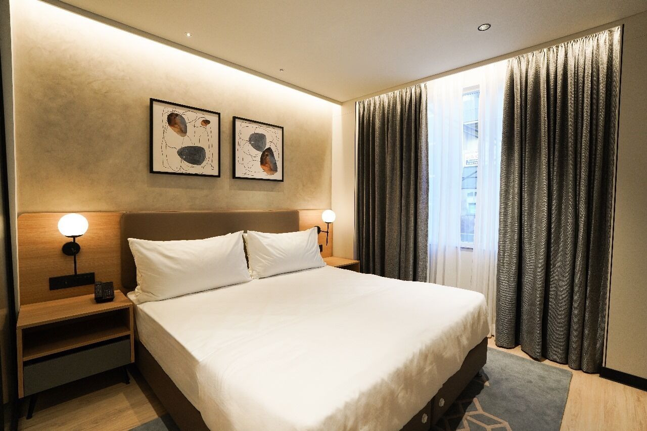 Ett hotellrum med en stor säng, två sängbord med lampor och konstverk på väggen.