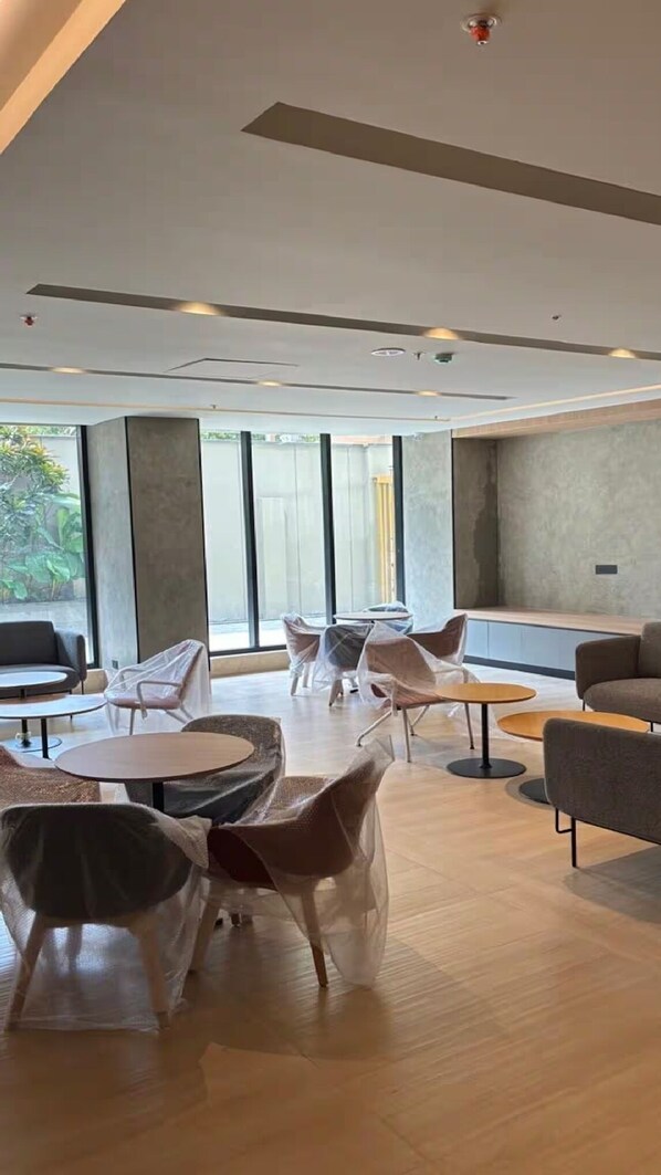 Un intérieur moderne avec des tables et des chaises rondes, de grandes fenêtres et une palette de couleurs neutres.