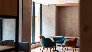 A modern interior with a seating area featuring sofas and tables, large windows with natural light, and a minimalist design. - Orchid Parc by evaddo stays (Bengaluru)