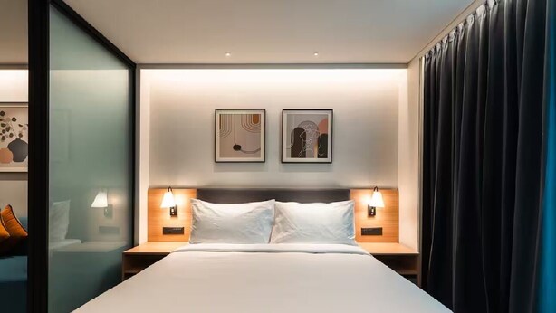 A modern hotel room with a large bed, two bedside tables with lamps, and two framed artworks on the wall. - Orchid Parc by evaddo stays (Bengaluru)