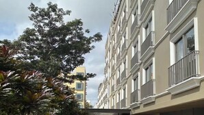 A paved walkway between buildings with a tree-lined path and a clear sky. - Orchid Parc by evaddo stays (Bengaluru)