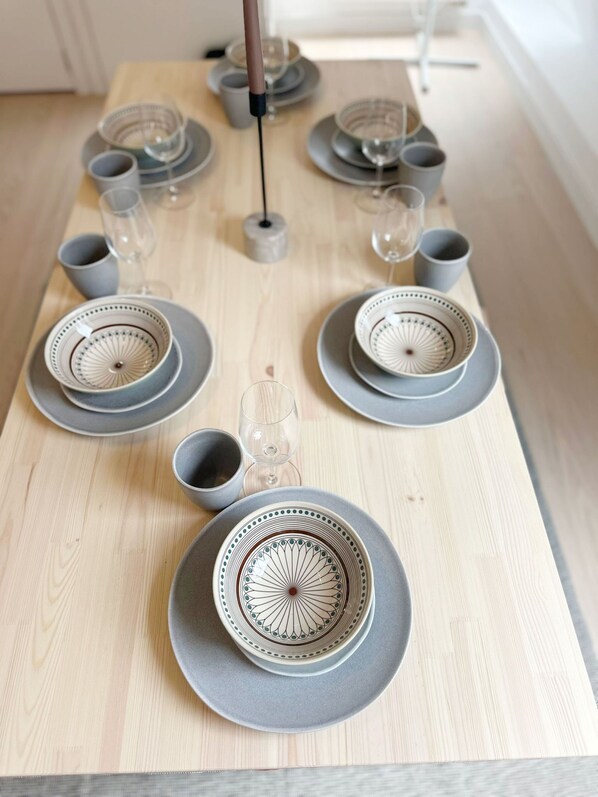 A neatly arranged dining table with grey plates, bowls, and glasses, set on a light wooden surface. - 2BR Apartment with Canal View in Ghent (Ghent)