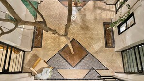 A spacious atrium with a high ceiling, tiled floors, and a central tree. - Riad DarDeco privé Marrakech medina (Marrakech)