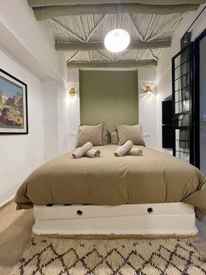 Ein modernes Schlafzimmer mit einem großen Bett, zwei Wandleuchten, einem Deckenventilator und einem gerahmten Bild an der Wand.