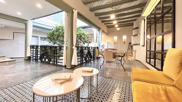 A spacious indoor area with a high ceiling, a yellow sofa, and a dining table with chairs. - Riad DarDeco privé Marrakech medina (Marrakech)