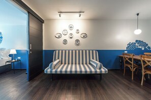 A modern room with a striped sofa, a dining table with chairs, and wall-mounted decorative plates. - Blu Monkey Boutique Naiharn Beach (Rawai)