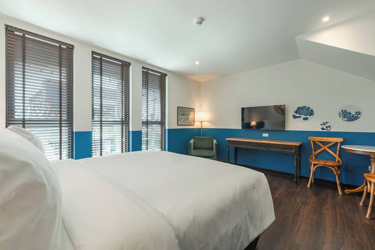 Ein Hotelzimmer mit Bett, Schreibtisch, Stuhl, Fernseher und Wanddekorationen.