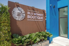 Schild für 'BLU MONKEY BOUTIQUE' mit einer Affen-Grafik, an der Naitharn Beach Phuket.