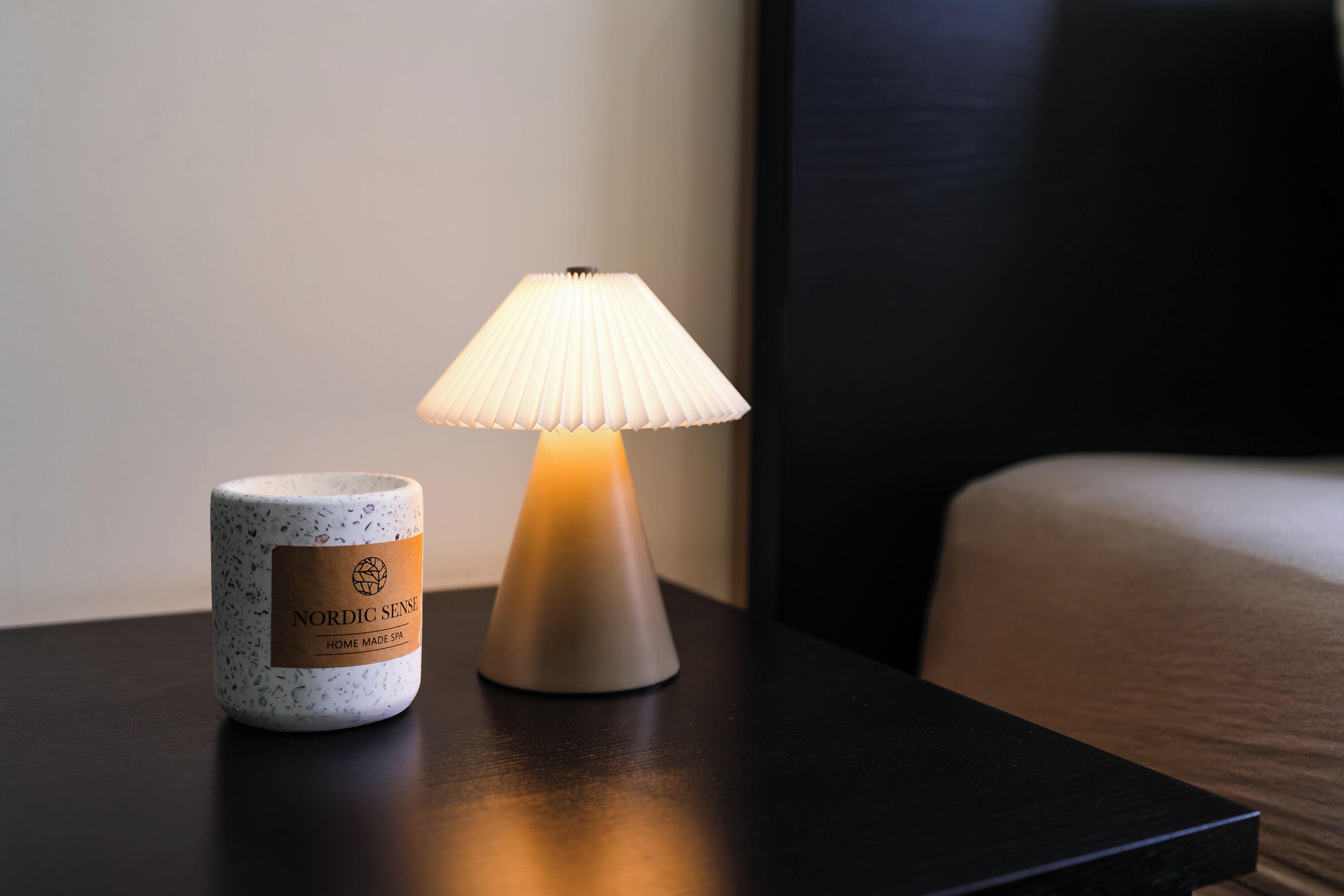 Una lampada Nordic Sense e una tazza in ceramica su un comodino in legno scuro.