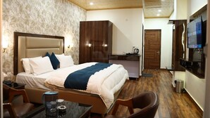 Une chambre d’hôtel équipée d’un lit, d’un bureau, d’une chaise, d’une télévision, d’une armoire et d’une kitchenette.
