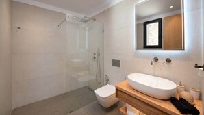 A modern bathroom with a glass-enclosed shower, a white sink, and a wooden vanity. - Vista Blue Villa Naxos - 2 (Τοπική Κοινότητα Βίβλου)