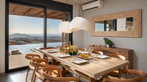A dining area with a large table set for six, overlooking a scenic view. - Vista Blue Villa Naxos - 2 (Τοπική Κοινότητα Βίβλου)