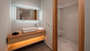 A modern bathroom with a large mirror, a wooden vanity, a white sink, and a glass shower enclosure. - Vista Blue Villas Naxos | 16 Guests (Τοπική Κοινότητα Βίβλου)