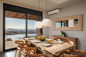 A dining area with a large table set for six, overlooking a scenic view. - Vista Blue Villas Naxos | 16 Guests (Τοπική Κοινότητα Βίβλου)