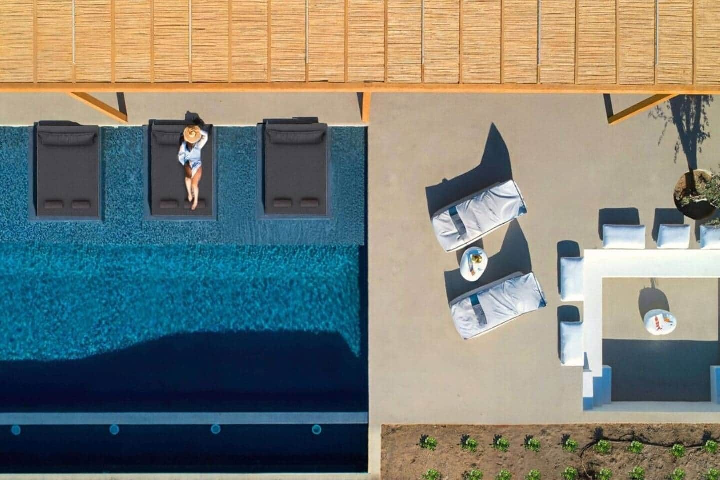 An aerial view of a pool area with lounge chairs and a table, and a separate section with a table and chairs.