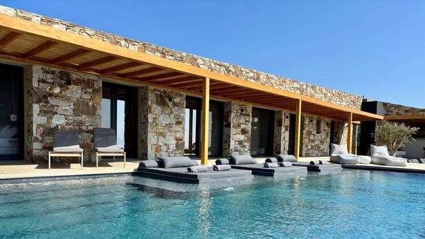 Una piscina con sillas de descanso y un edificio de piedra con vigas de madera.