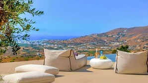 Una terraza con mesas al aire libre y vistas panorámicas de un pueblo costero.