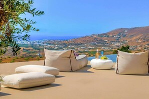 Eine Terrasse mit Sitzgelegenheiten und Blick auf eine Küstenlandschaft.
