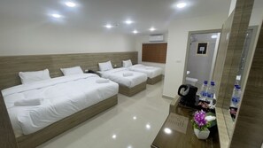A hotel room with three beds, a wooden headboard, a mirror, a coffee maker, and a water dispenser. - Petra Desert Hotel  (Wadi Musa)
