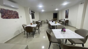 A conference room with multiple tables and chairs, air conditioning units, and artwork on the walls. - Petra Desert Hotel (Wadi Musa)
