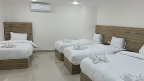 A hotel room with four beds arranged in a row, each with white bedding and pillows. - Petra Desert Hotel (Wadi Musa)