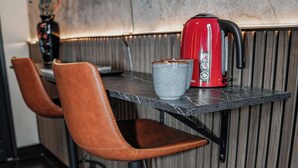 A modern kitchen with a marble countertop, a red kettle, and two brown leather bar stools. - Cozy 5BR Apt in the Heart of Ghent (Ghent)