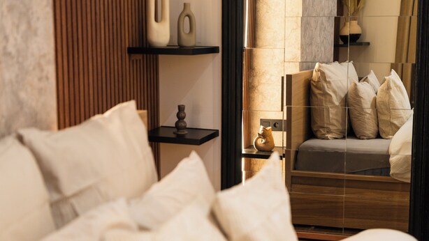 A modern bedroom with a bed, pillows, a nightstand, and a vase. - Cozy 5BR Apt in the Heart of Ghent (Ghent)