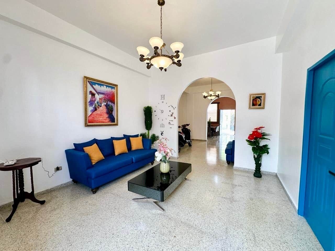 A spacious lobby with a blue sofa, a coffee table, and a chandelier.
