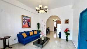 A spacious lobby with a blue sofa, a coffee table, and a chandelier. - Colonial Home with Private Terrace and Jacuzzi (Santo Domingo)