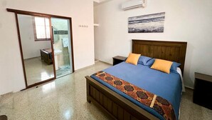 A bedroom with a bed, a ceiling fan, an air conditioning unit, and a bathroom visible through a glass door. - Colonial Home with Private Terrace and Jacuzzi (Santo Domingo)