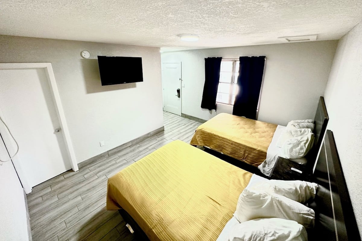 A room with two beds, a TV, and a door.