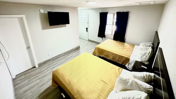 A room with two beds, a TV, and a door. - Soho Inn Waldo (Waldo)
