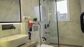Een moderne badkamer met een marmeren vloer, een wit wastafelmeubel, een toilet en een douchecabine van glas.